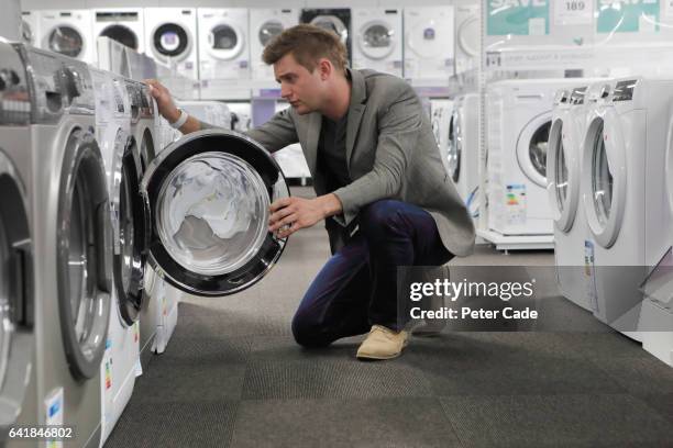 man looking inside appliance in shop - gas washer dryer stock pictures, royalty-free photos & images