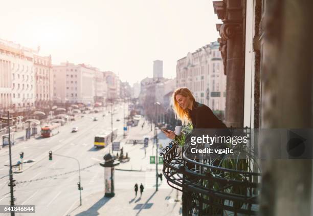 femme seule sur le balcon de l’hôtel - escapade urbaine photos et images de collection