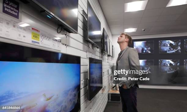 man looking at televisions in shop - tv store stock pictures, royalty-free photos & images