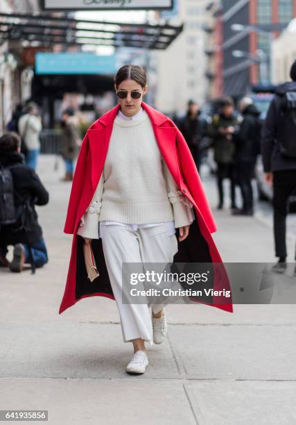 Guest wearing a red coat, white knit, cropped pants outside Tory Burch on February 14, 2017 in New York City.