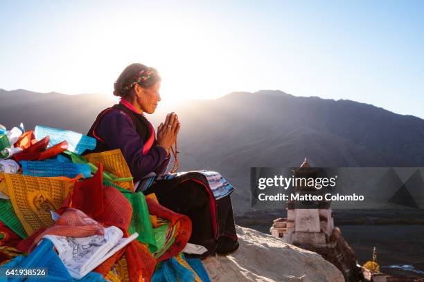 old woman praying at sunset on top of hill, tibet - tibet stock photos et images de collection