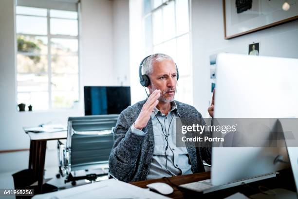 confident businessman video conferencing at desk - voip stock pictures, royalty-free photos & images