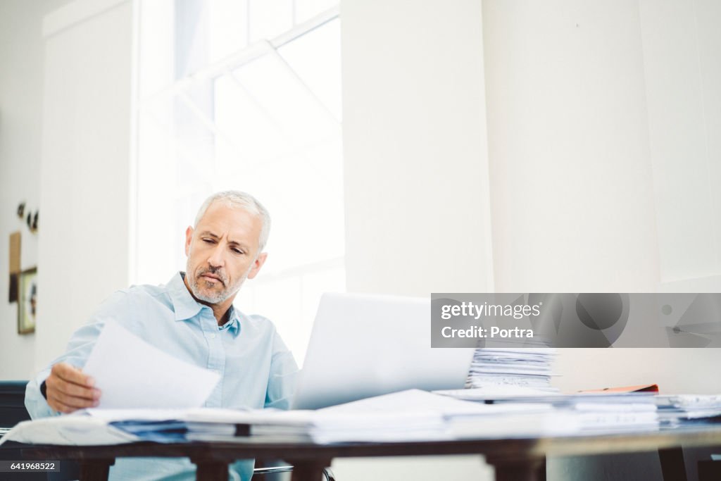 Businessman reading document at desk in office