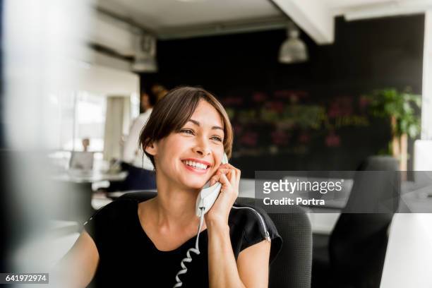 fröhliche geschäftsfrau mit telefon im büro - festnetzanschluss stock-fotos und bilder