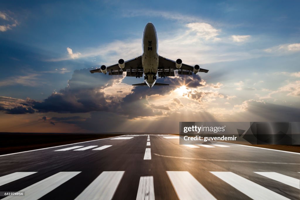 Passenger airplane taking off at sunset