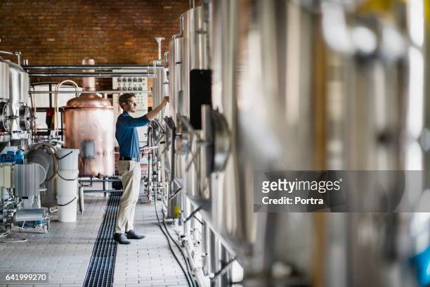 trabajador de sexo masculino operar maquinaria en fábrica de cerveza - destilería fotografías e imágenes de stock