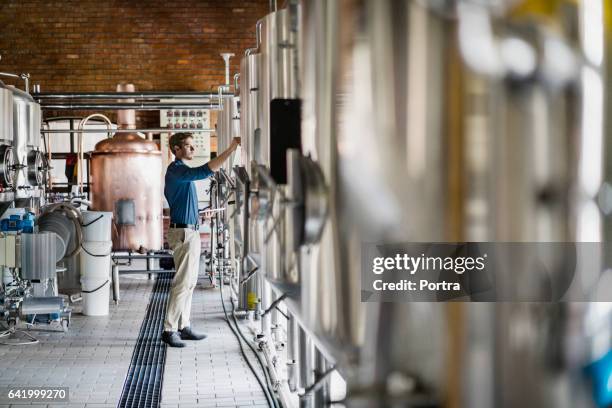 mannelijke werknemer bedienen van machines in de brouwerij - distilleerderij stockfoto's en -beelden
