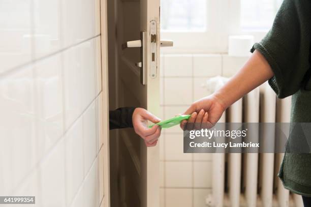 woman handing sanitary pad to other woman - bathroom door imagens e fotografias de stock