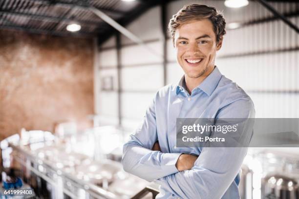 brazos de trabajador de sexo masculino feliz de pie cruzan en cervecería - un solo hombre joven fotografías e imágenes de stock