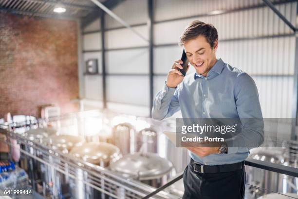worker using tablet pc and smart phone in brewery - brewery tank stock pictures, royalty-free photos & images