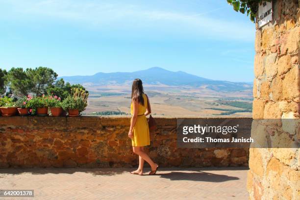 woman in yellow dress looking over the scenic tuscany landscape of val d'orcia from pienza - yellow dress - fotografias e filmes do acervo