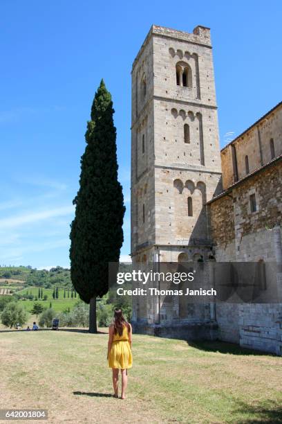 women in yellow dress looking at abbazia di sant'antimo, val d'orcia, tuscany - abbazia di santantimo foto e immagini stock