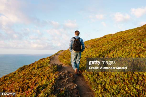 tourist with backpack walking on a hiking trail along the ocean - sintra portugal stock pictures, royalty-free photos & images