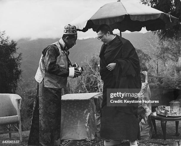 Tenzin Gyatso, the 14th Dalai Lama, shows interest in the camera held by Palden Thondup Namgyal , the eldest son of Tashi Namgyal, the Chogyal or...