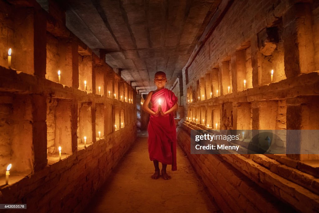 Novice monnik bidden binnen de tempel volledige branden kaarsen Bagan Myanmar