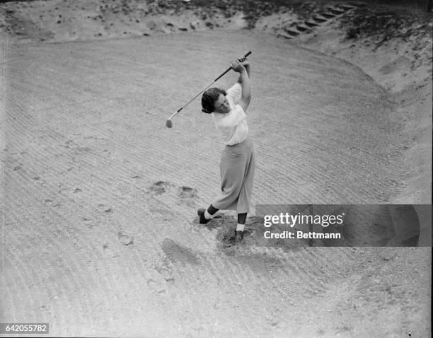 Miss Patty Berg, of Minneapolis, Minnesota, newest golfing sensation, shows the formidable array of clubs she carries around the golf course with her...