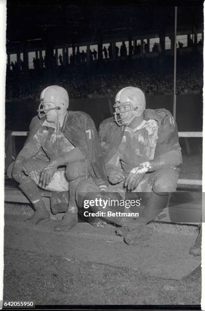 Derrell Palmer, and Len Ford of the Cleveland Browns sit wet and mud splattered, as they watch teammates battle the New York Giants on October 25th,...