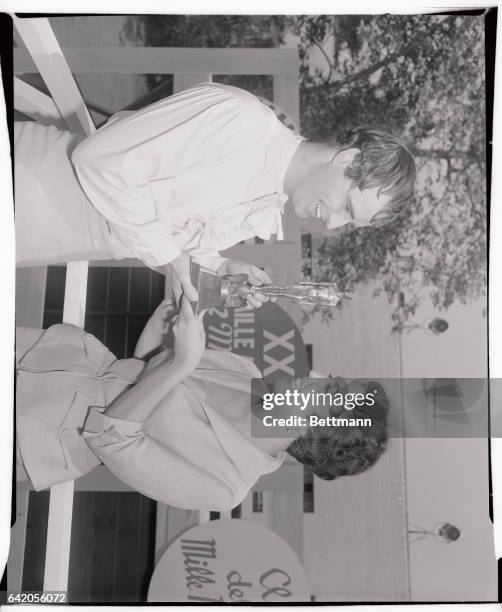 Mexican actress Katy Jurando shows her Ariel trophy to actor Marlon Brando after receiving the "Oscar" like statuette from the Mexican Consul-General...