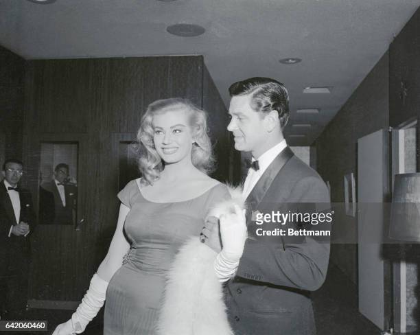 Sultry film star Anita Ekberg smiles happily as she holds hands with British actor Anthony Steele, with whom she has been romantically linked by...