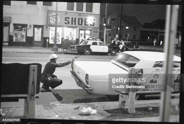 Los Angeles: Move In On Sniper. A policeman aims his revolver at building from which a sniper was taking potshots at passing cars during rioting...