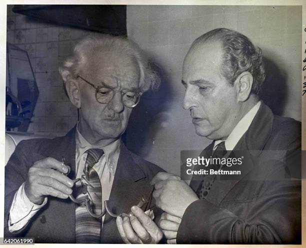 New York, NY: Harry Blackstone, renowned magician, and Joseph Dunninger, equally famous mentalist, are examining a pair of handcuffs that fugured in...