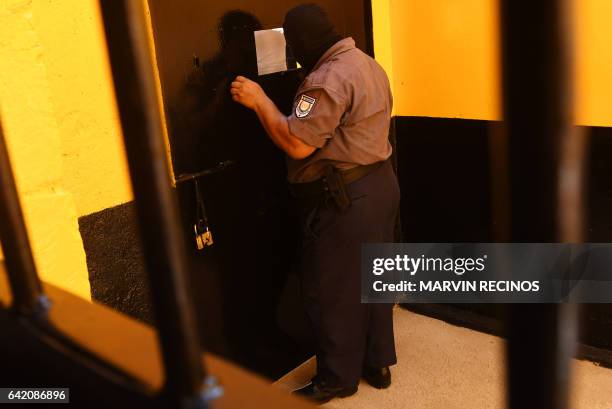 Prison guards wearing a balaclava stands guard at the entrance of the San Francisco Gotera prison, 165 km from San Salvador, on February 16, 2017. In...