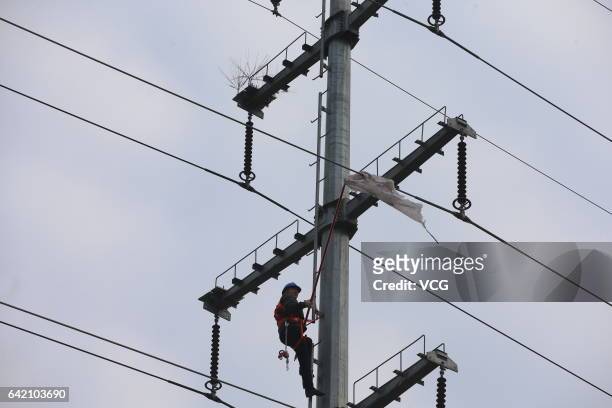 Worker tries to remove a piece of plastic from the high-voltage wire on February 14, 2017 in Xiangyang, Hubei Province of China. The technicians of...