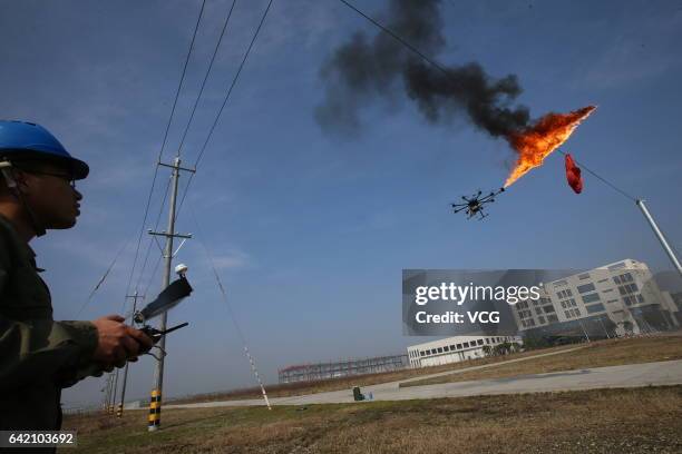 An unmanned aerial vehicle, operated by a technician, spews fire to remove a piece of plastic from the high-voltage wire on February 10, 2017 in...