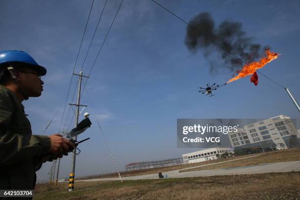 An unmanned aerial vehicle, operated by a technician, spews fire to remove a piece of plastic from the high-voltage wire on February 10, 2017 in...