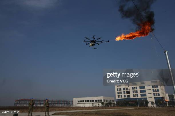 An unmanned aerial vehicle, operated by a technician, spews fire to remove a piece of plastic from the high-voltage wire on February 10, 2017 in...