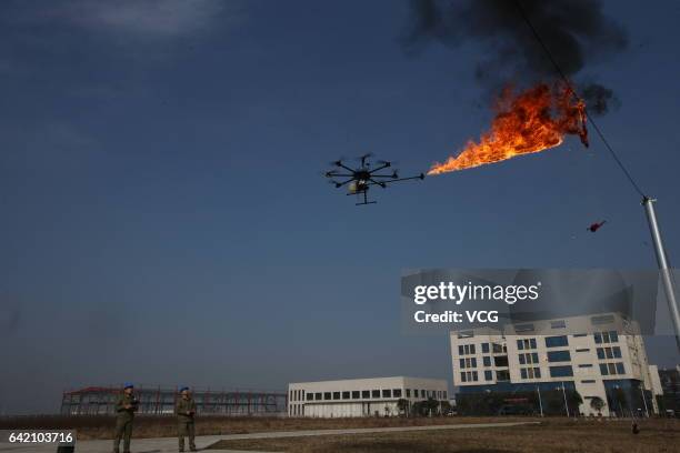 An unmanned aerial vehicle, operated by a technician, spews fire to remove a piece of plastic from the high-voltage wire on February 10, 2017 in...