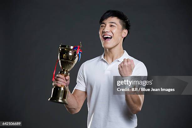 young man cheering with a trophy - mens health 2015 awards stock pictures, royalty-free photos & images