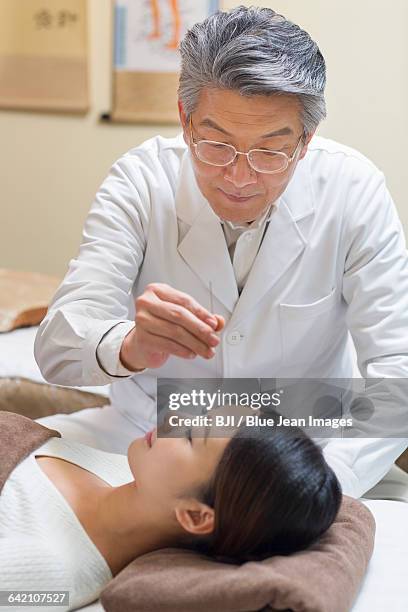 young woman receiving acupuncture - acupuncture elderly stock pictures, royalty-free photos & images