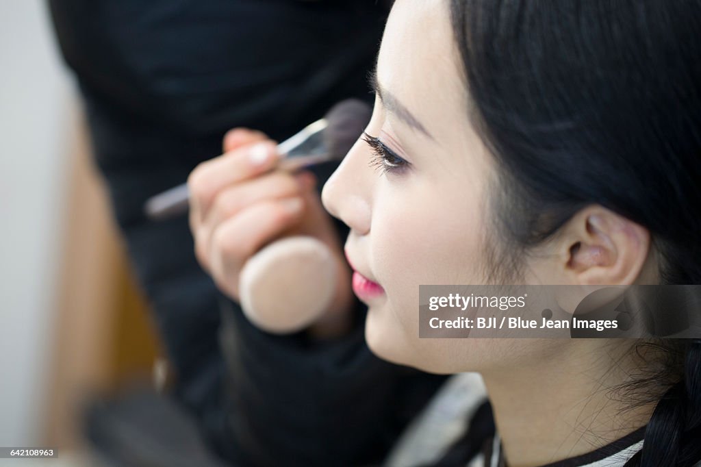 Makeup artist applying make-up to young woman