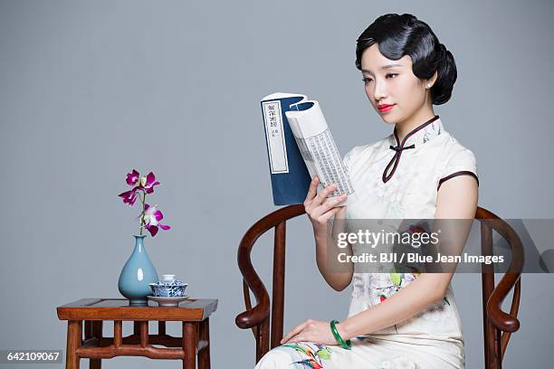 young beautiful woman in traditional cheongsam reading book - the cheongsam photos et images de collection