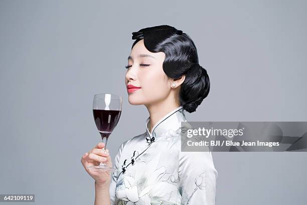 young beautiful woman in traditional cheongsam with red wine - asian woman wavy hair stock-fotos und bilder