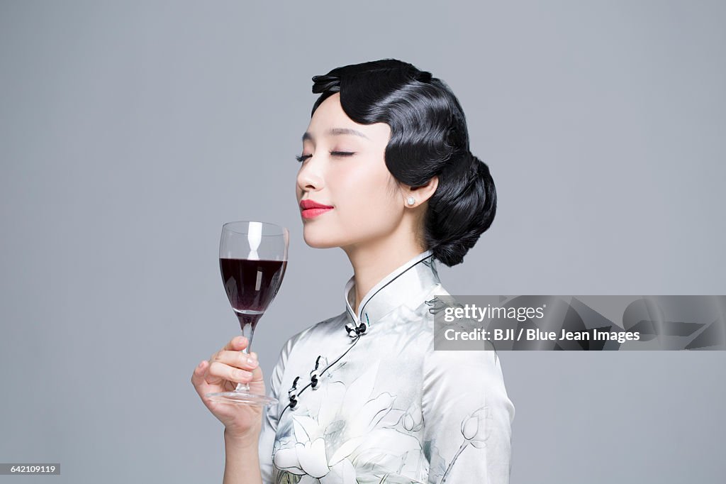 Young beautiful woman in traditional cheongsam with red wine