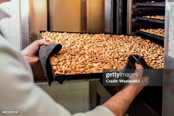 italy, manufacturing of traditional torrone in confectionery shop, roasted almonds on tray - nougat stock pictures, royalty-free photos & images