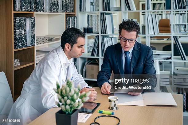 man in suit explaining documents to doctor in medical office - businessman in suit ストックフォトと画像