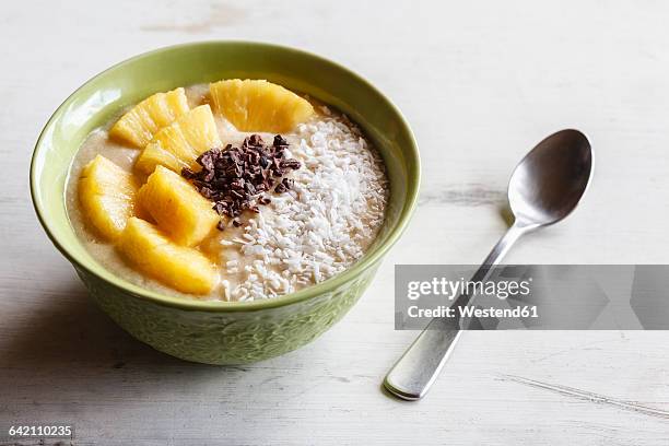 bowl of fruit smoothie garnished with pineapple slices, coconut flakes and chocolate shaving - coconut shaving stock pictures, royalty-free photos & images