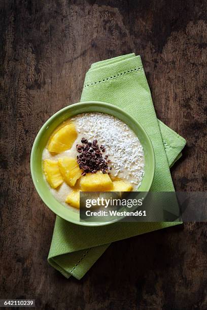 bowl of fruit smoothie garnished with pineapple slices, coconut flakes and chocolate shaving - coconut shaving stock pictures, royalty-free photos & images