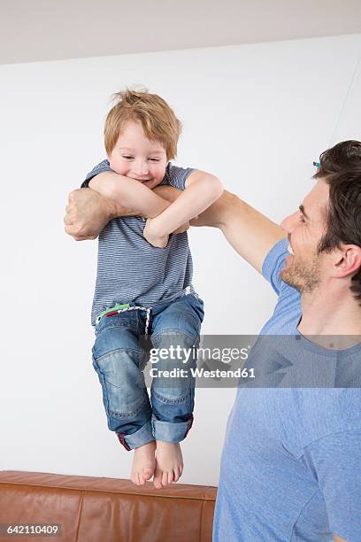 son doing chin ups on father's arm - boys in pullups stockfoto's en -beelden