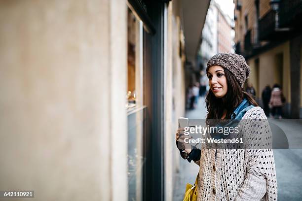 spain, barcelona, smiling young woman in the city looking at shop window - barcelona shopping stock pictures, royalty-free photos & images