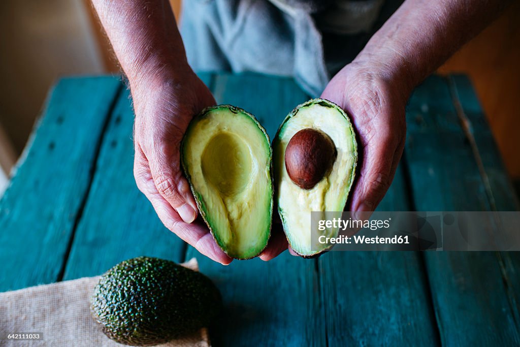 Hands holding two halves of an avocado