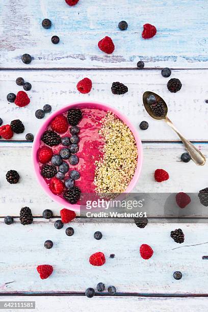 bowl with fruit smoothie garnished with berries and hemp seeds - hemp seed fotografías e imágenes de stock