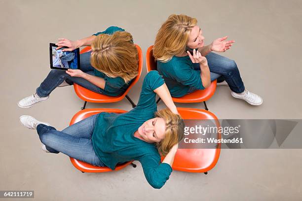 woman sitting on chairs using portable devices, multitasking - sitting and using smartphone studio stock-fotos und bilder