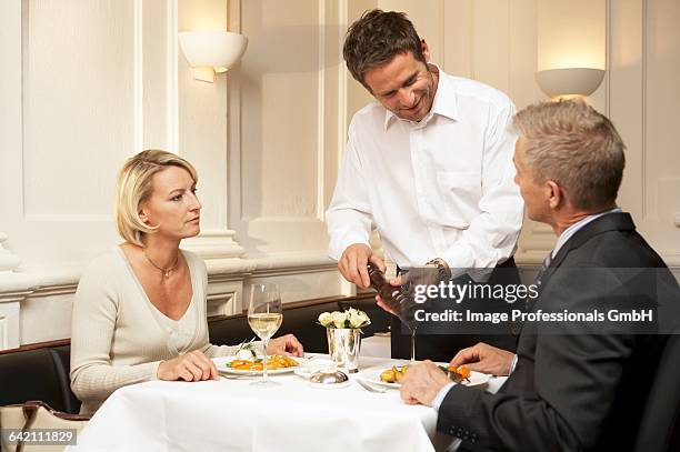 waiter seasoning a mans food in a restaurant - pepper mill stockfoto's en -beelden