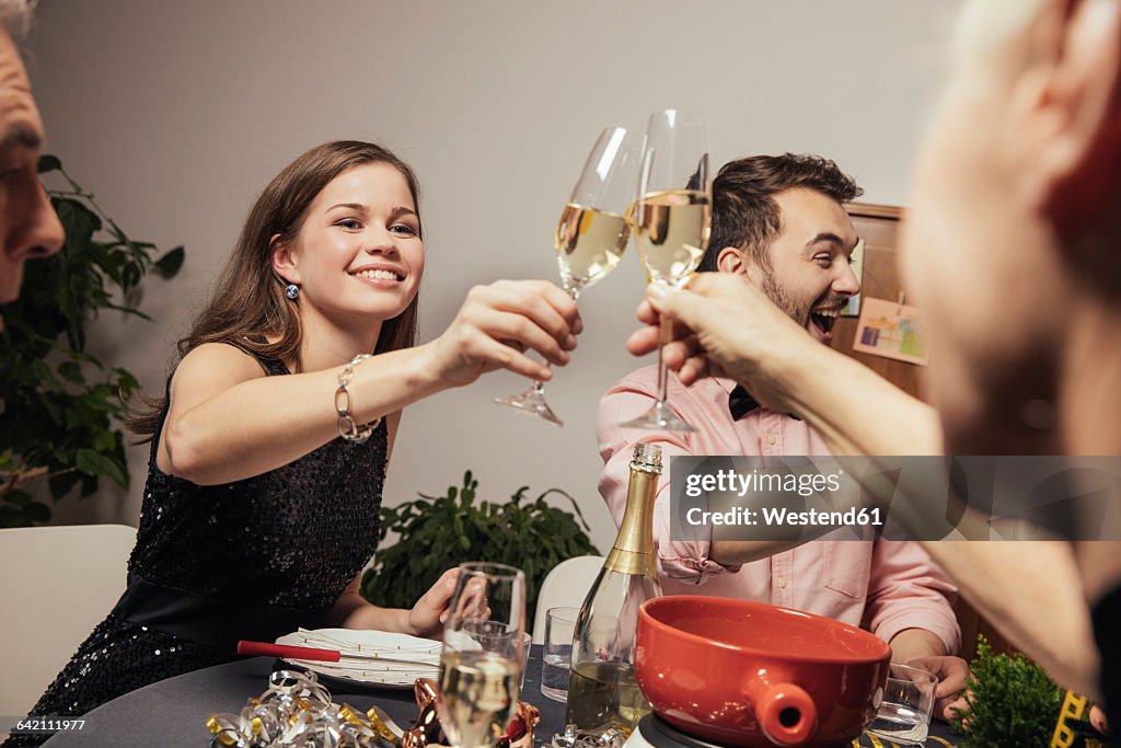 Laughing friends clinking glasses with champagne at New Year's Eve