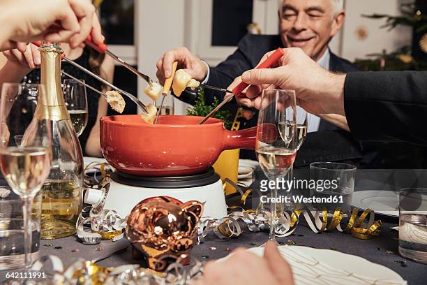 friends eating cheese fondue on new year's eve - fondue stock pictures, royalty-free photos & images