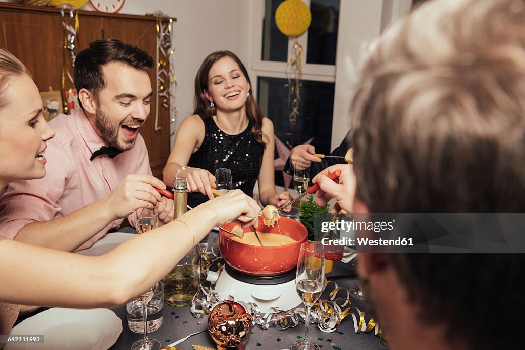 Friends eating cheese fondue on New Year's Eve